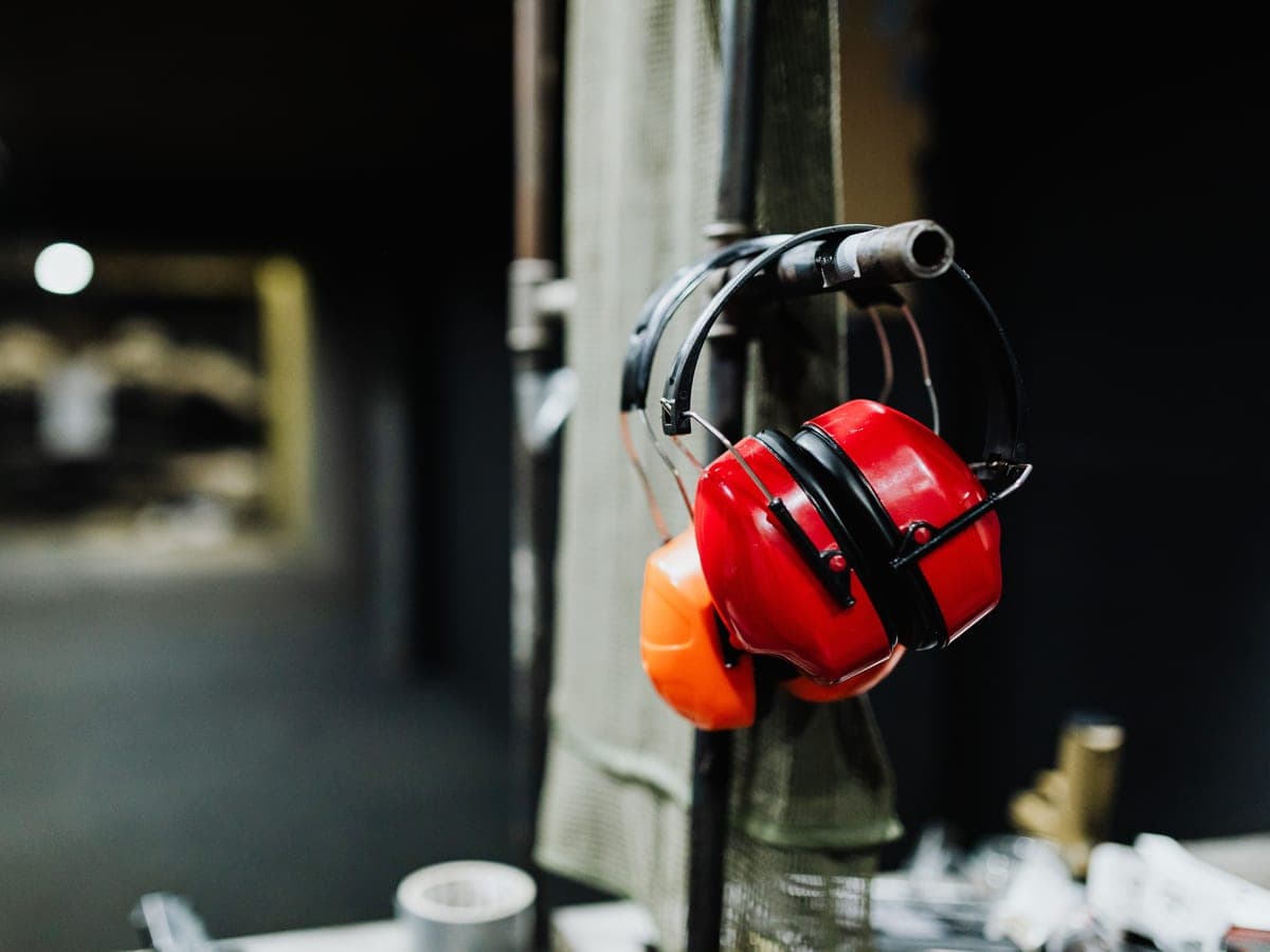 Red electronic earmuffs hanging on a post at an indoor shooting range — Bench & Berm, shooting range gear & hearing/eye protection