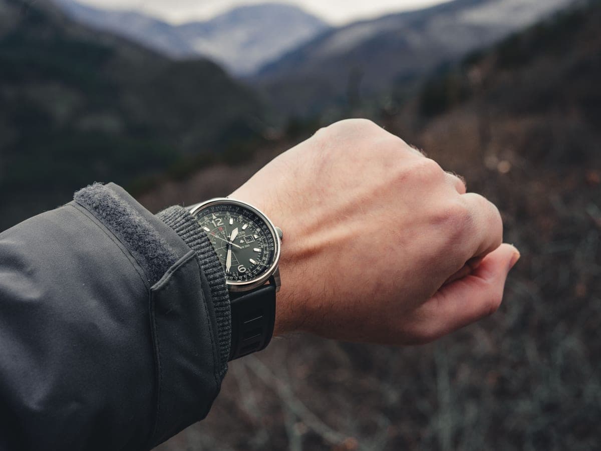 A field watch on a wrist against a mountain trail backdrop — Bezel & Bearing, rugged gps & outdoor watches