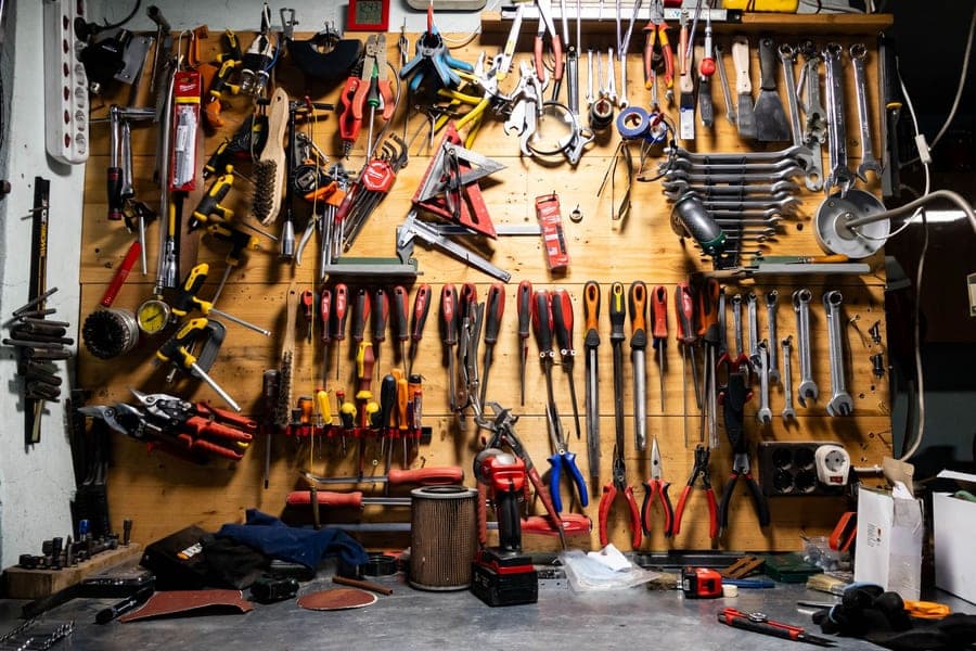 Hand tools, wrenches and screwdrivers hung in rows on a wooden pegboard wall above a workbench — Garage & Workbench, garage & home shop setup