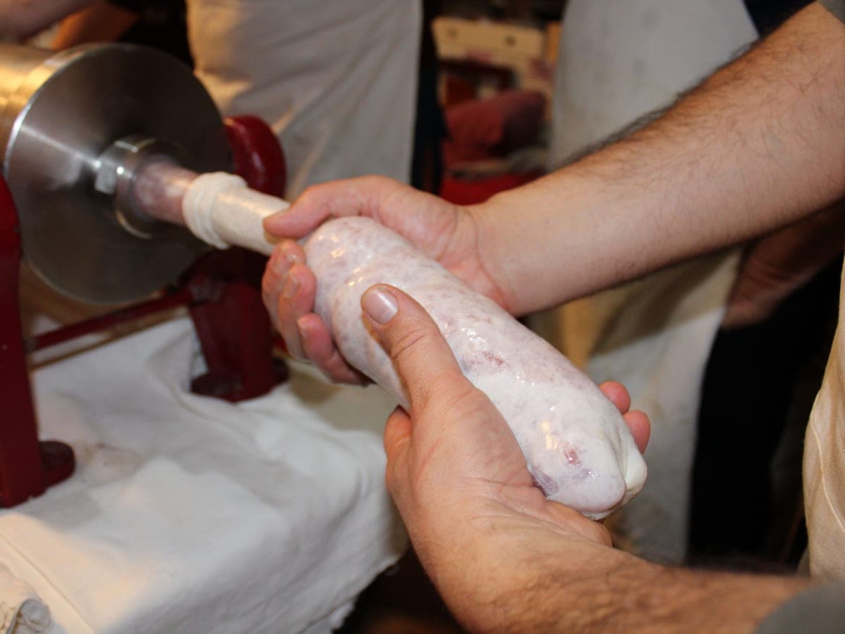 Hands feeding casing onto a sausage stuffer — Grind & Cure, meat & game processing gear