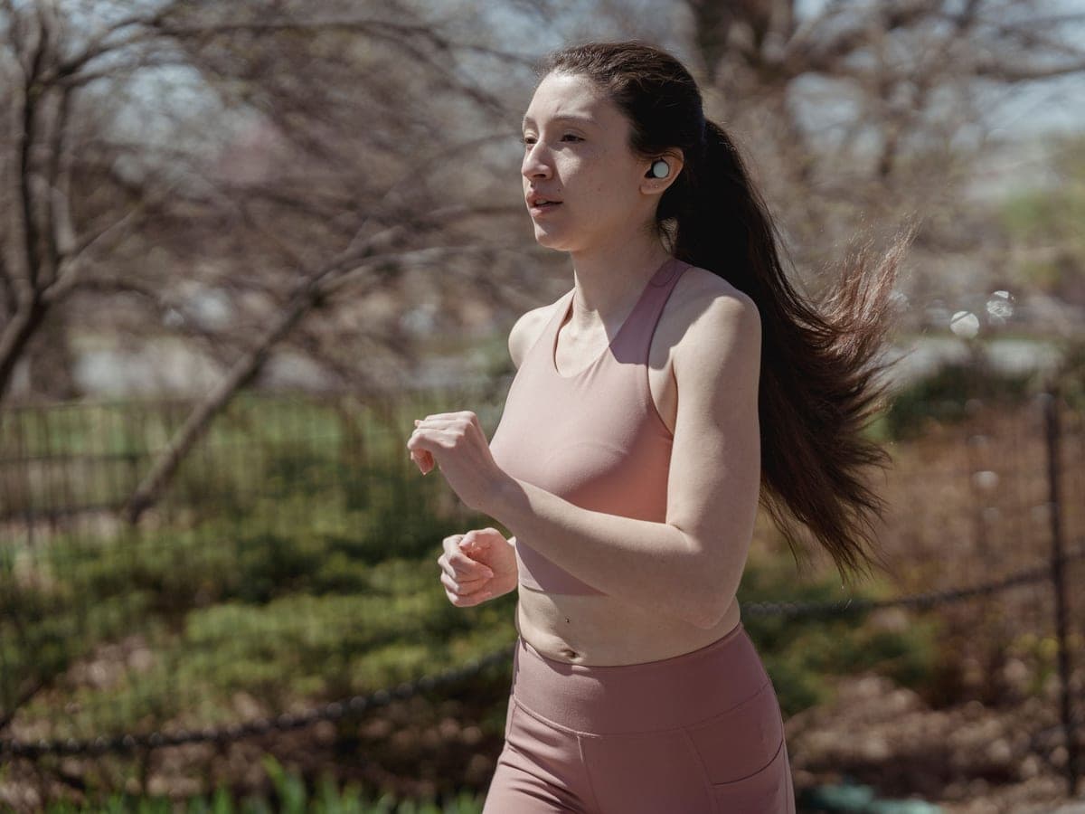 A runner on a city bridge wearing earbuds — Open Ear Club, open-ear & workout earbuds