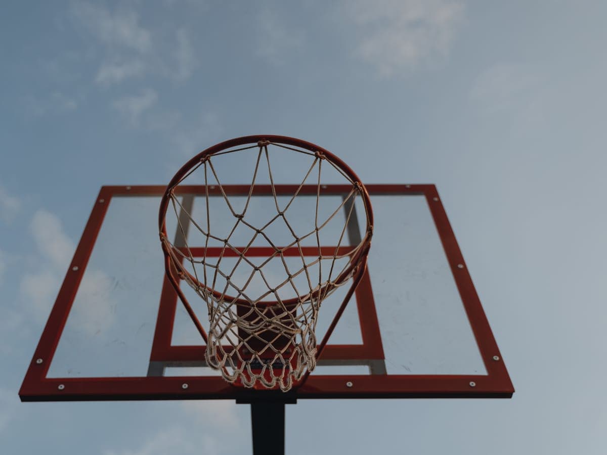 A basketball hoop and backboard seen from below against the sky — Rim & Rebound, basketball hoops & driveway sports