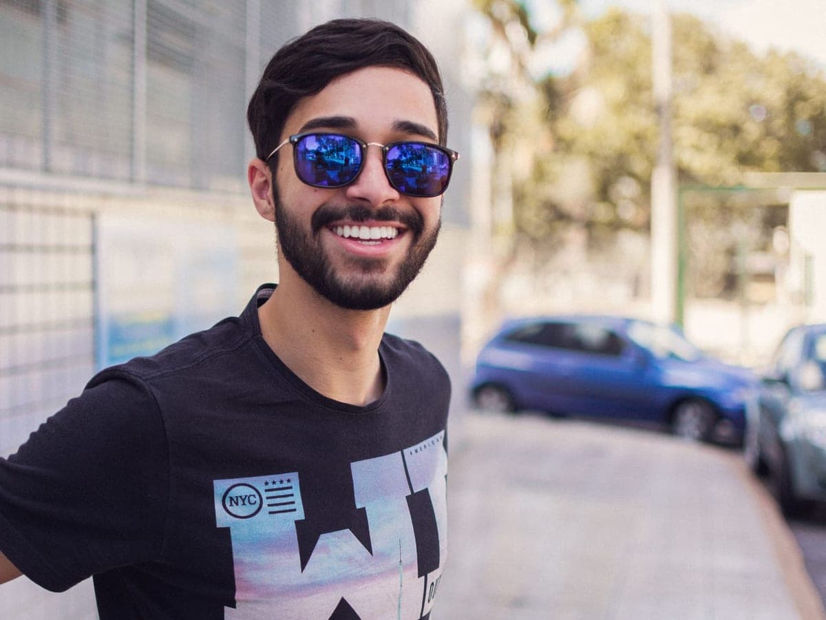 A smiling man wearing mirrored sunglasses on a sunny street — Shade & Signal, smart glasses & camera eyewear
