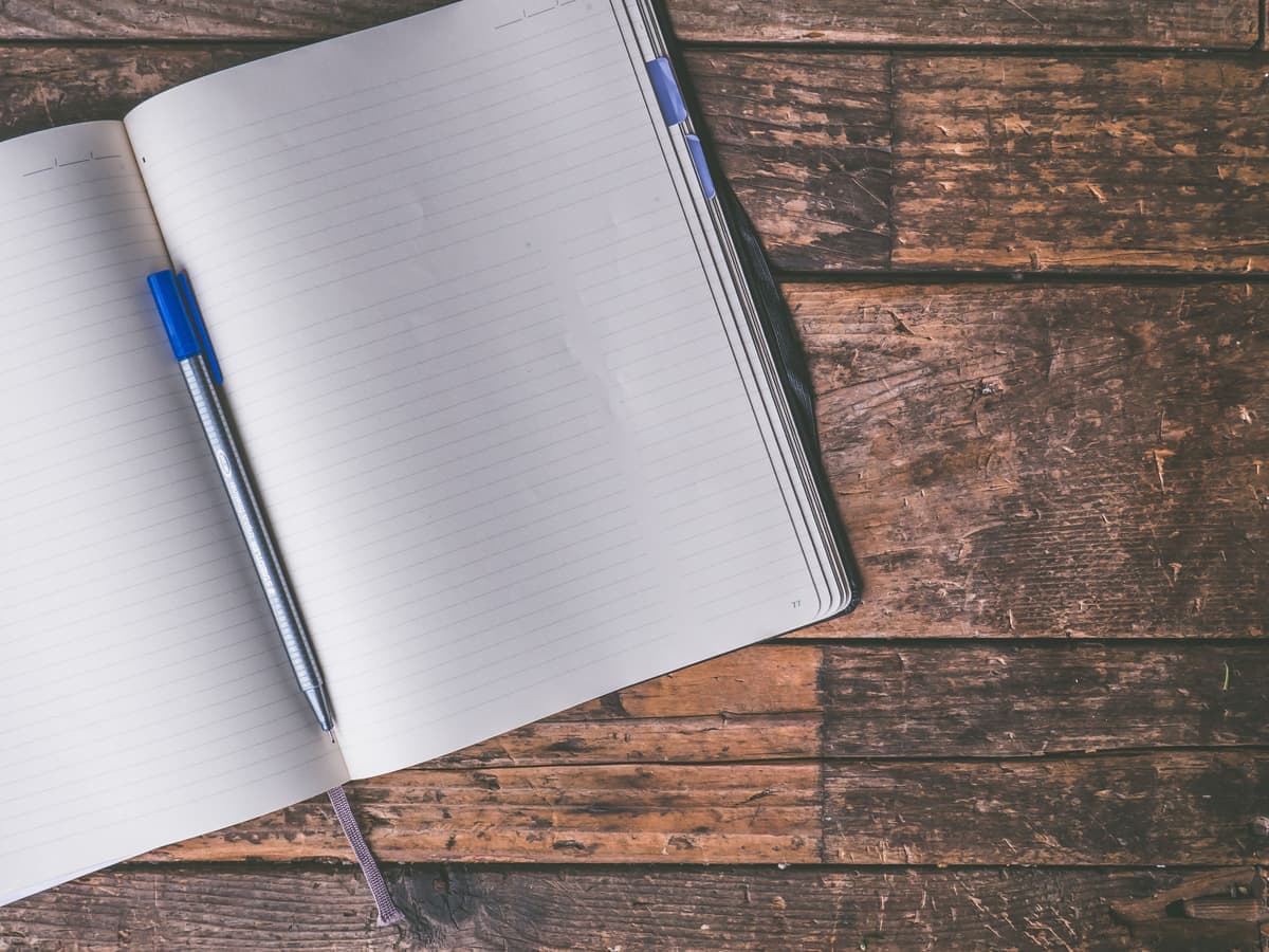 An open notebook and pen on a wooden table