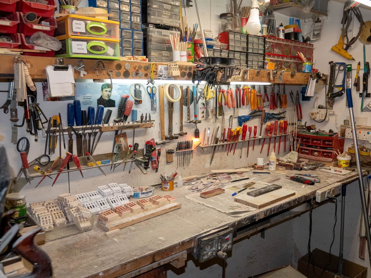 A one-person workshop bench with hand tools hung in rows on the wall above it
